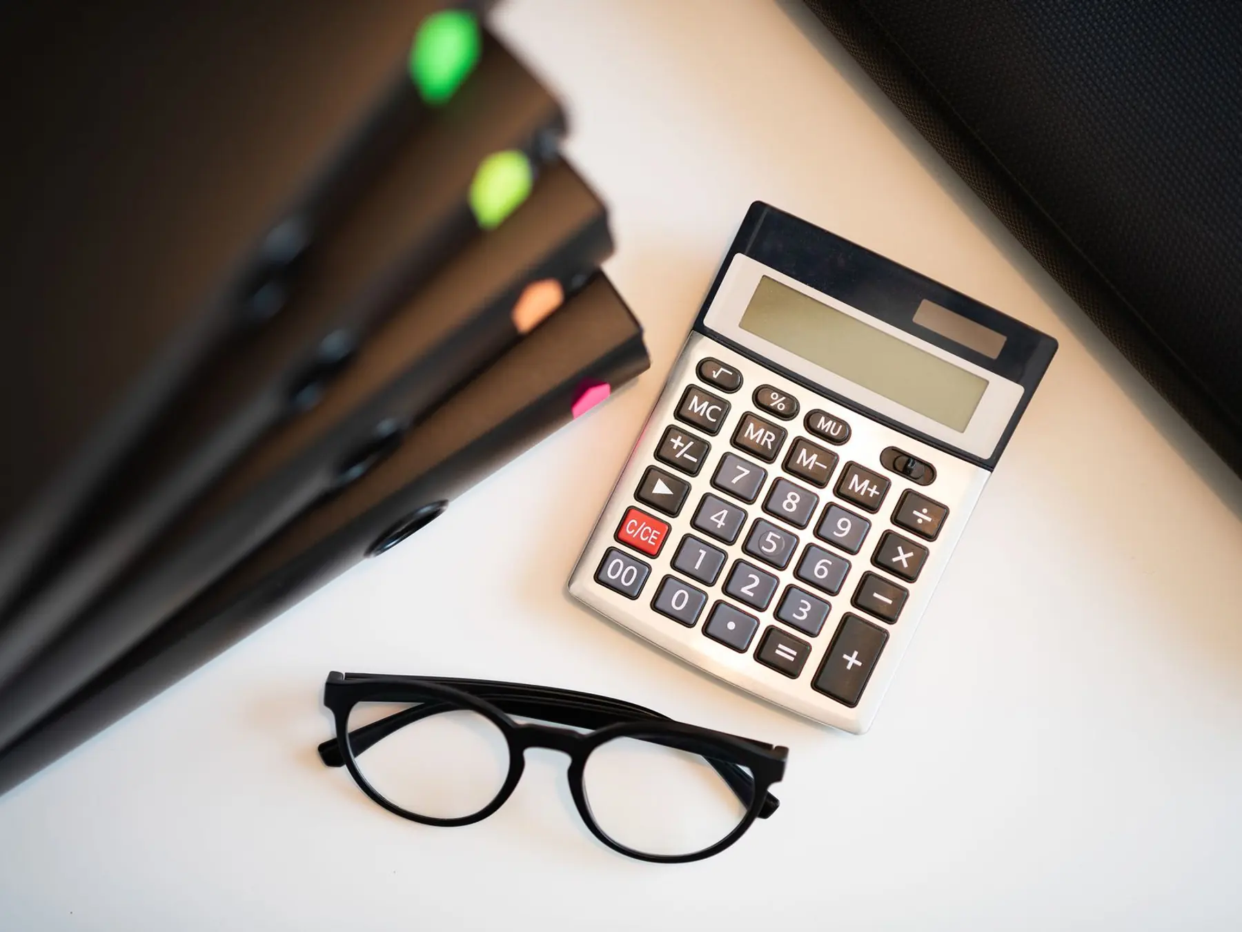 Mesa de despacho con la calculadora, las gafas y las carpetas de las cuentas de la comunidad