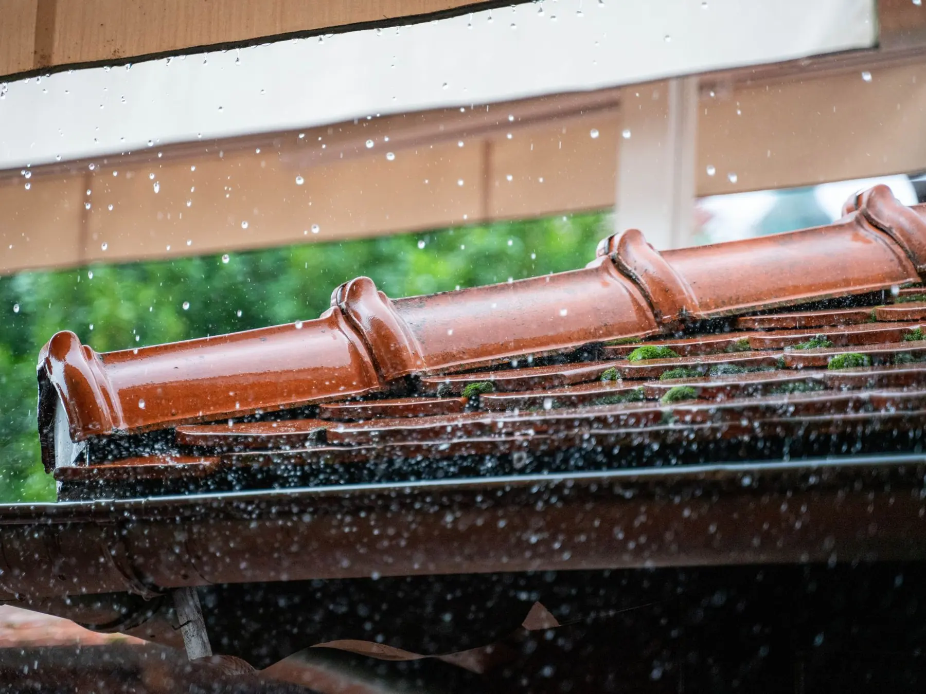 Agua de lluvia cayendo desde el alero de tejas de un edificio